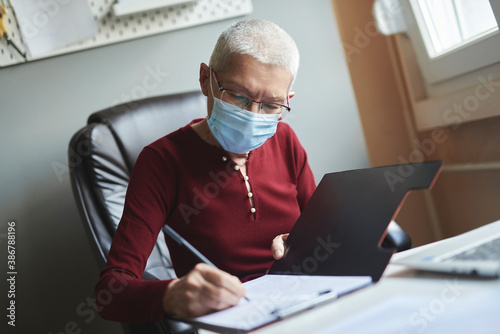 Senior woman working from home, with mask on