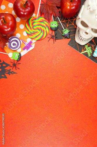 Happy Halloween Trick or Treat theme flat lay with candy and lollipops, skull and pumpkin on textured orange background. Top view blog hero header creative composition with negative copy space.