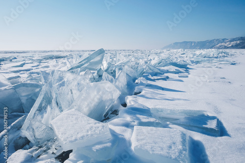 Crystal clear ice of Lake Baikal. Shards of ice, cracks on the surface. Winter landscape for background, banners.