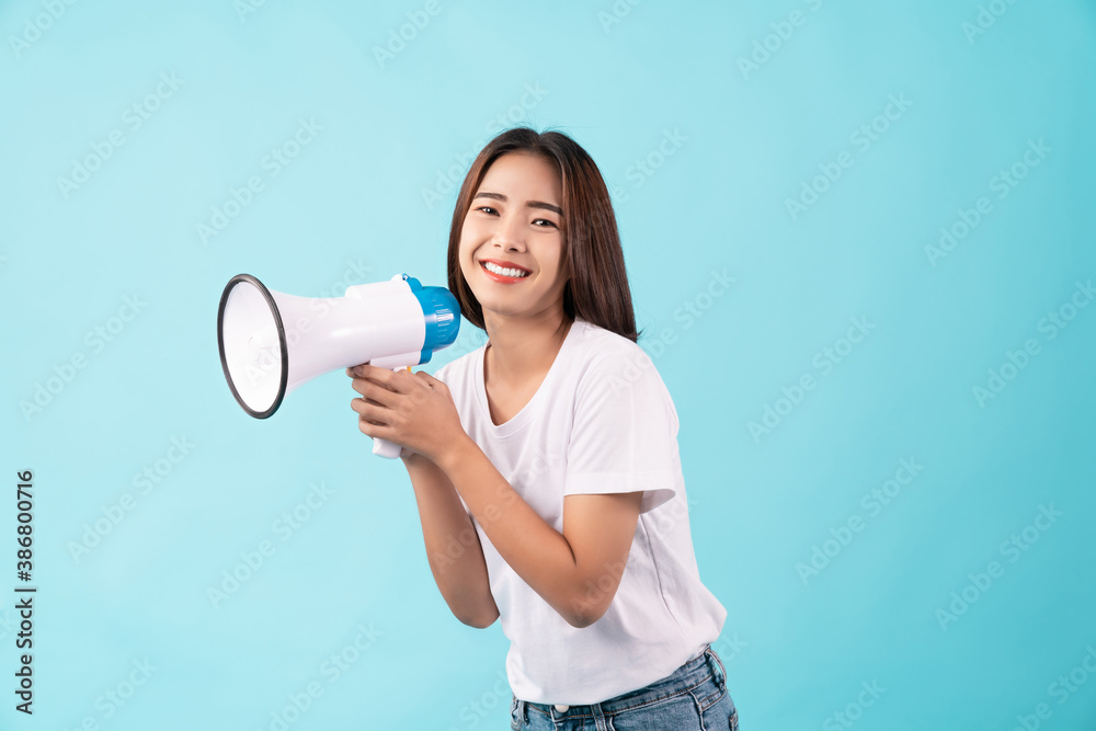 Young Asian woman standing on a blue background and hand touches on mouth with yelled for something. Young Asian woman standing on a blue background and hand touches on mouth with yelled for something.