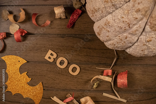 Halloween flat lay. Pumpkin, potpourri, orange bat, and Boo, word made from wooden letters on wooden background photo