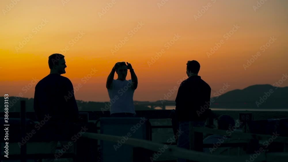 Silhouette of friends on a rooftop, enjoying the sunset above the San Francisco city, the Golden gate bridge in the background, during dusk, in California, USA - Handheld, pan shot Silhouette of friends on a rooftop, enjoying the sunset above the San Francisco city, the Golden gate bridge in the background, during dusk, in California, USA - Handheld, pan shot