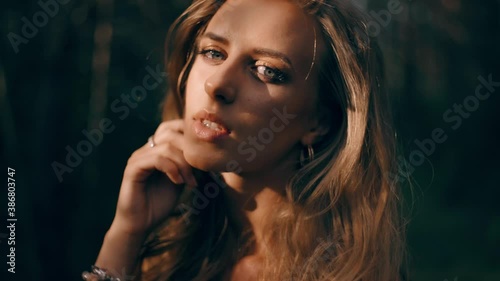 Young beautiful woman with perfect makeup and skin is posing on the sun light. Luxury glamour model is touching her hair and closing eyes sensual. Slow motion close up portrait