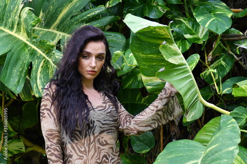 Portrait of a beautiful Latin descent woman outdoors in spring, summer or fall season. Lens flares and sunlight brighten the image with soft light. She wears a lace dress and sultry stare.
