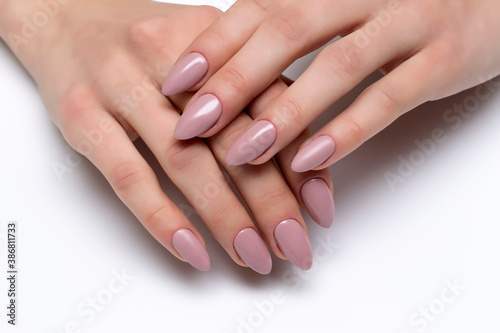 Nude, beige gel extended manicure on sharp long nails close-up on a white background