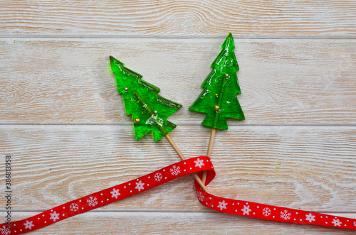 A Lollipop in the shape of a christmas tree and a red ribbon. Holiday sweets for child
