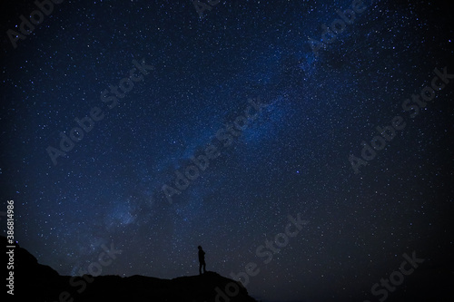 Silhouette of boy / man on the hill. Stargazing at Oahu island, Hawaii. Starry night sky, Milky Way galaxy astrophotography. 