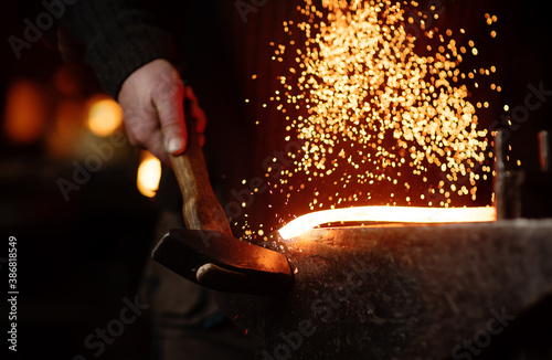 Foto The blacksmith hits the red-hot workpiece in the forge with a hammer and glowing