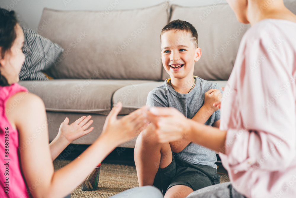 joyful family plays funny game joining hands near soft sofa in light living room. joyful family plays funny game joining hands near soft sofa in light living room.