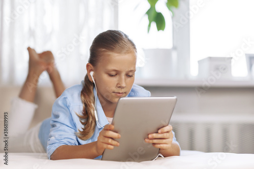 Happy teenage girl with blue eyes in a light room, sits with a tablet and communicates using a video call. Online education, Online learning.