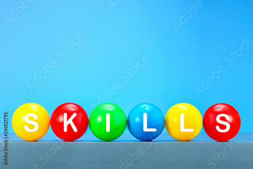 Line of colorfull balls with word SKILLS against blue background with copy space.