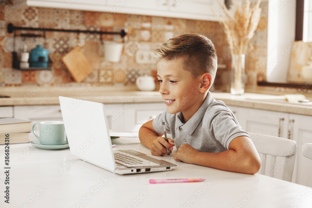 Boy does homework in the kitchen with a laptop online, talking to the teacher. Distance learning, online education, Boy does homework in the kitchen with a laptop online, talking to the teacher. Distance learning, online education,