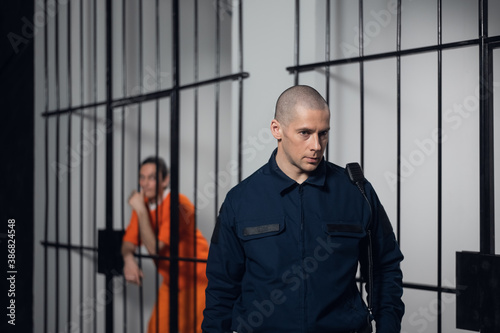 A uniformed overseer in an asian prison makes an evening tour of the cells with prisoners.