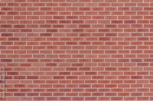 Full frame abstract view of a modern traditional brick wall background, with textured red and orange bricks in a running bond brickwork pattern
