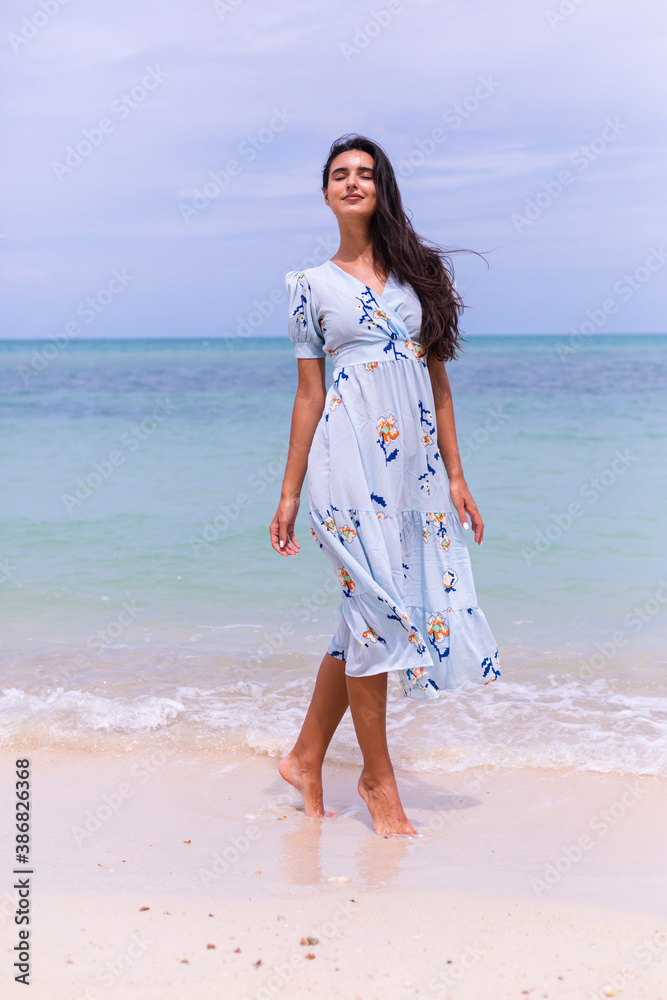 Romantic portrait of woman in long blue dress on beach by sea at windy day. Romantic portrait of woman in long blue dress on beach by sea at windy day.