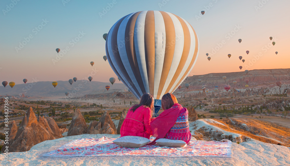 Hot air balloon flying over spectacular Cappadocia - Japanese girls watching hot air balloon at the hill of Cappadocia