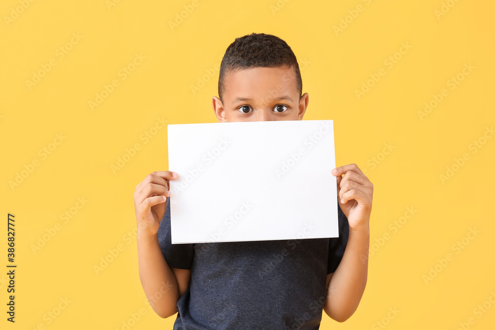 Little African-American boy with blank paper sheet on color background Little African-American boy with blank paper sheet on color background
