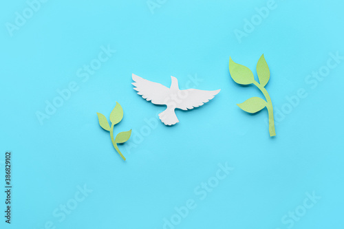 Paper dove and olive branches on color background. International Day of Peace