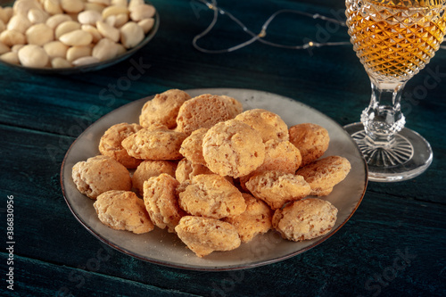 Amaretti, traditional Italian almond cookies, with a glass of Amaretto liqueur and almonds, on a dark blue wooden background