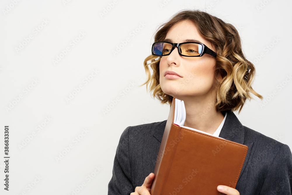 Business woman with notepad and glasses work light background cropped view of suit model. Business woman with notepad and glasses work light background cropped view of suit model.