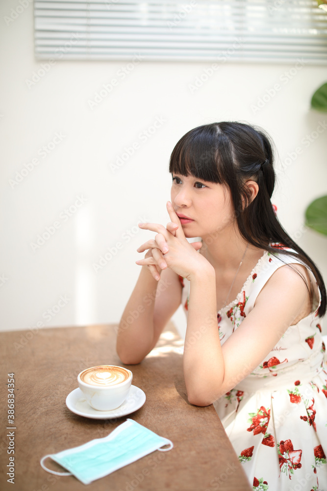 Young Asian Woman sitting with mask at coffee in coffee shop Young Asian Woman sitting with mask at coffee in coffee shop
