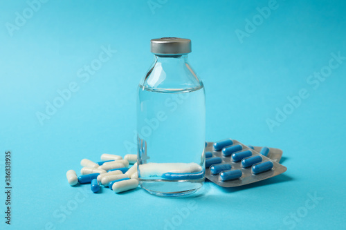 Pills and bottle with medicine on blue background