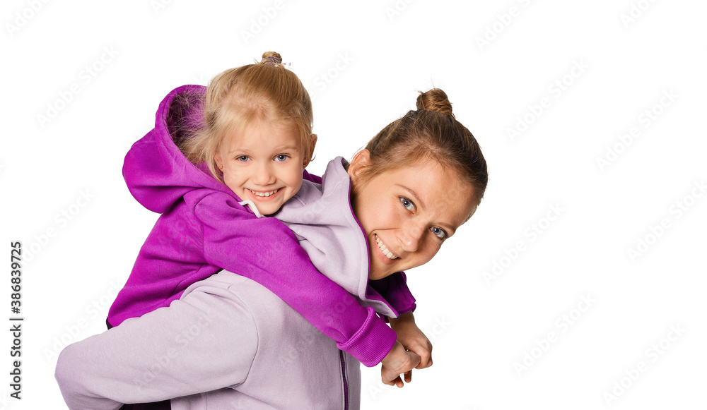 Smiling blonde kid girl and woman in stylish jumpsuits with hood posing over gray background. Cute daughter 4-5 year old hugging her mother. Mock up copy space lifestyle concept. Smiling blonde kid girl and woman in stylish jumpsuits with hood posing over gray background. Cute daughter 4-5 year old hugging her mother. Mock up copy space lifestyle concept.