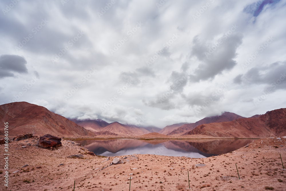 Lake surround by mountains with desert landscape and cloudy sky in Xinjian, China