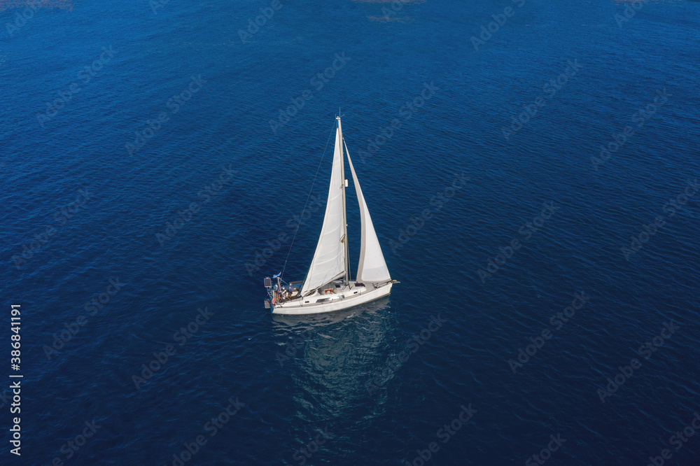 Sailing boat with white sails, rippled sea background