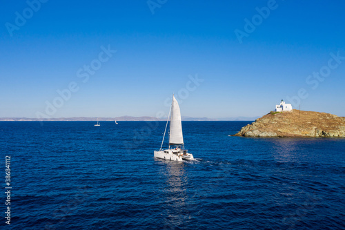 Sailing boat catamaran with white sails, rippled sea background