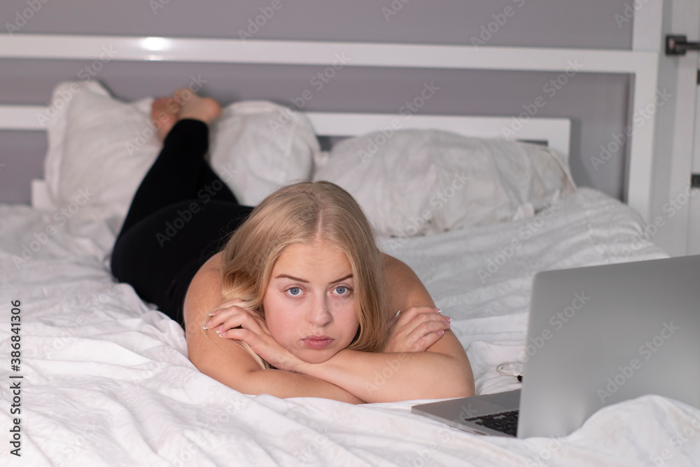 beautiful flirty blonde with laptop on bed with white sheets. pretty people at isolation. beautiful flirty blonde with laptop on bed with white sheets. pretty people at isolation.