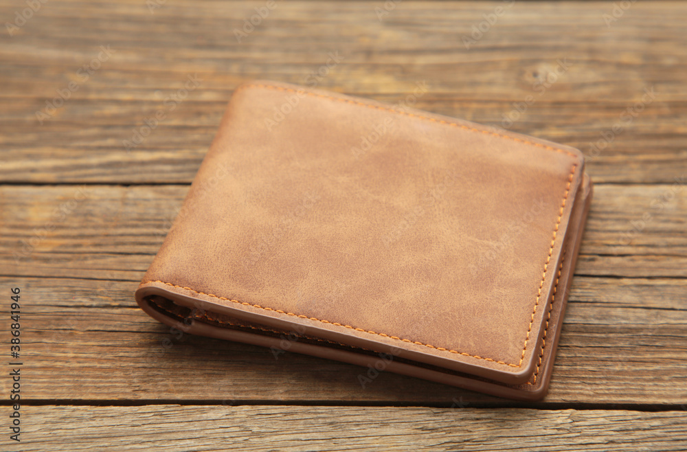 Brown shiny wallet on grey wooden background Brown shiny wallet on grey wooden background