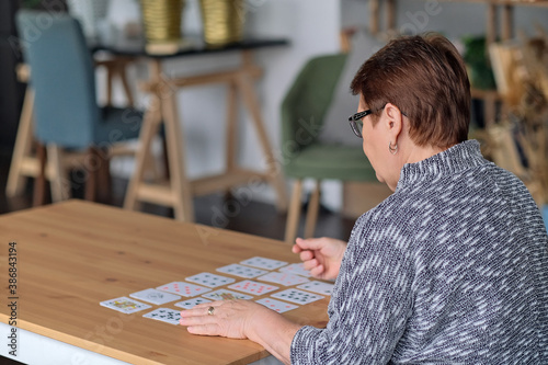 senior woman playing solitaire at home. Happy old lady plays an intellectual game