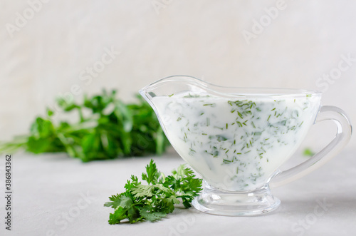 white sauce with spices in a gravy boat on a white background.