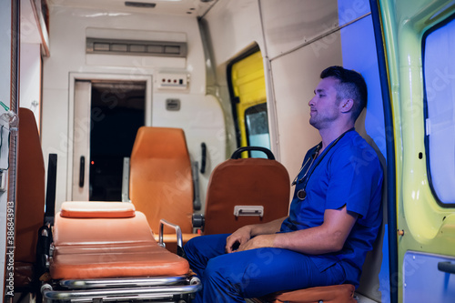 Tired paramedic on duty, sitting in an ambulance car, waiting for the next call.