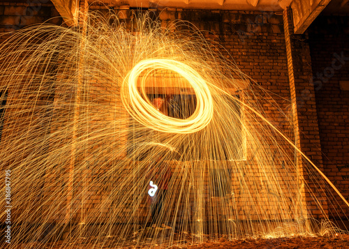 Picture playing fireworks, turning the line into a wave shape, sparks on the light, an amazing fire dance in an old white brick building and beautiful reflections