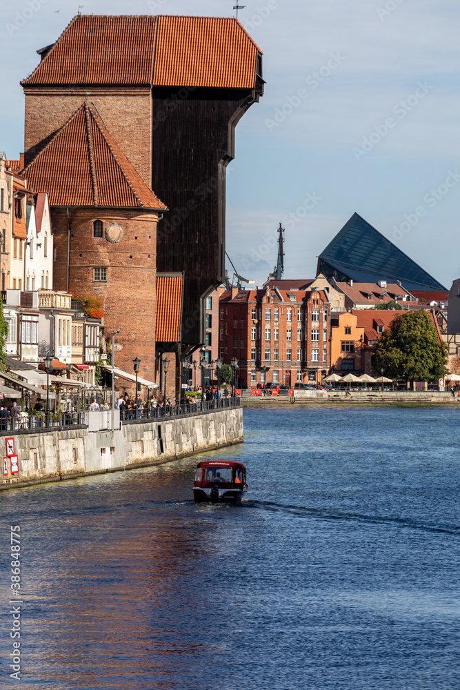 Obraz premium The largest medieval port Crane in Europe and historic buildings on the Dlugie Pobrzeze over the Motlawa River in Gdansk, Poland.