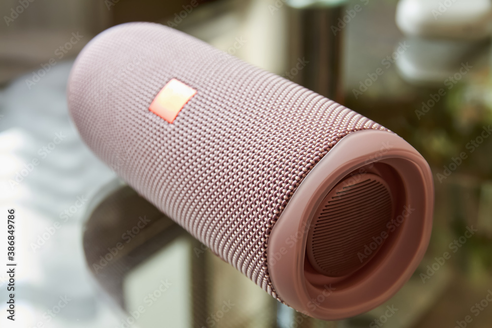 A part of portable pink bluetooth and wireless speaker on a glass surface. Close-up, selective focus A part of portable pink bluetooth and wireless speaker on a glass surface. Close-up, selective focus