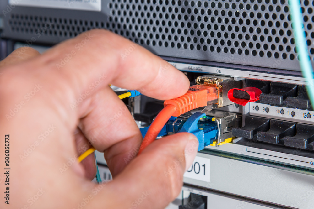 Hand of computer engineer connecting fiber optic cable in server Hand of computer engineer connecting fiber optic cable in server