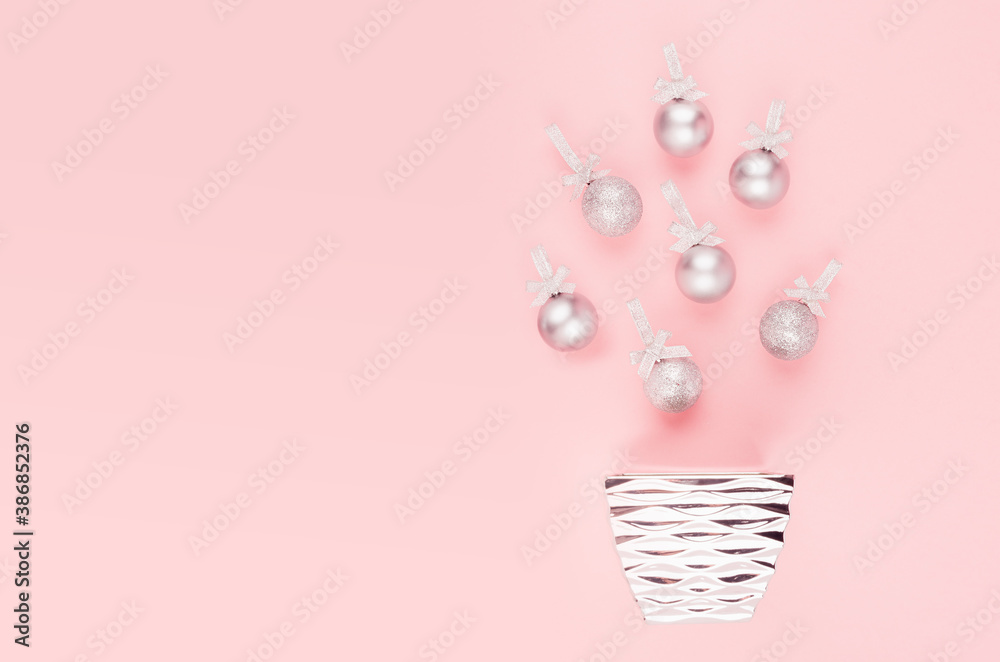 Silver christmas balls with glitter bow and ribbon flying above bowl as christmas tree on pastel soft light pink background, top view, copy space. Silver christmas balls with glitter bow and ribbon flying above bowl as christmas tree on pastel soft light pink background, top view, copy space.