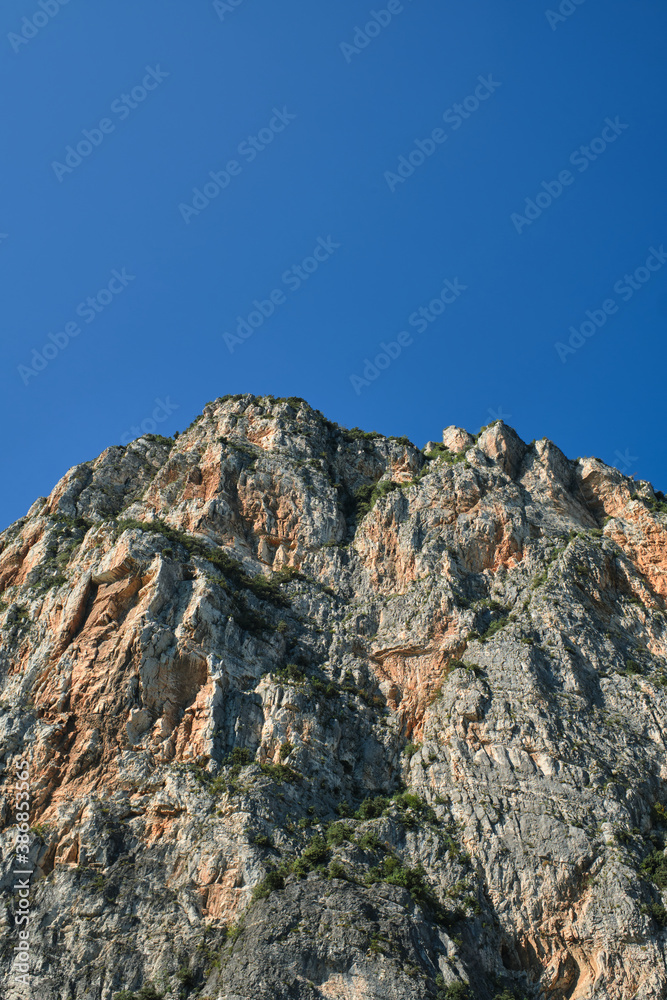The tops of the yellow peaks of the rocks. Red stones on a blue background. Gray rocks at high altitude. Alps top on blue sky. Rough rocky stones. The tops of the yellow peaks of the rocks. Red stones on a blue background. Gray rocks at high altitude. Alps top on blue sky. Rough rocky stones.