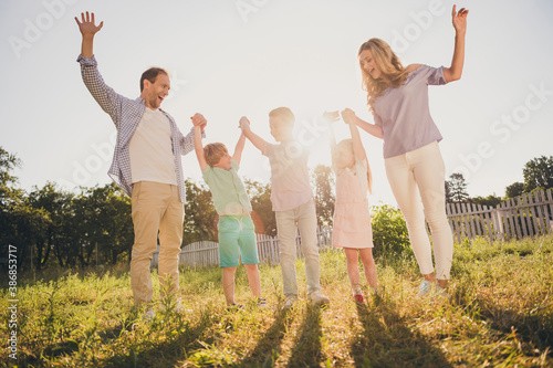 Full length photo of positive fun family outdoors garden weekend gathering mommy daddy hold hand laughing small kids adopted boys girls in evening summer sunshine