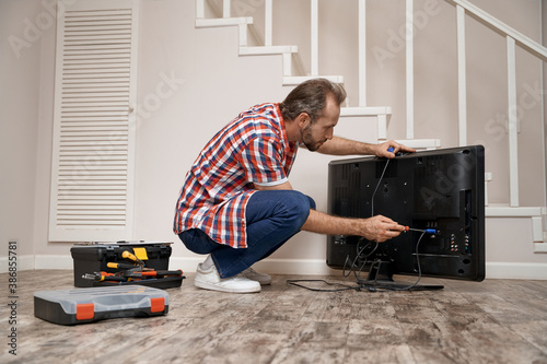 Young caucasian service man fixing tv set