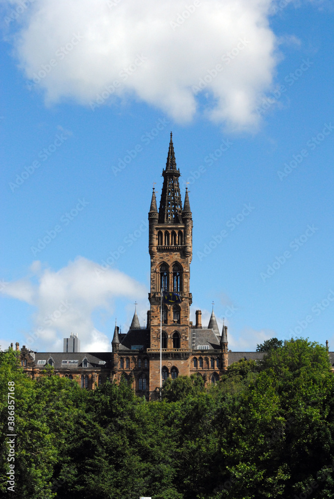 Ornate 19th century Gothic Stone Tower & Trees seen against Blue Sky 