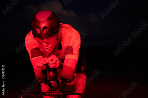 triathlon athlete riding bike fast at night