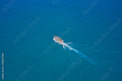 Speed boat movement at high speed aerial view. High-speed yacht of white color fast motion on blue water in the rays of the sun top view. Top back view of the boat.