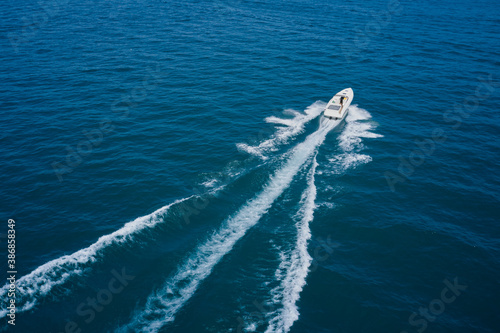 Top view of a white boat sailing to the blue sea. Aerial bird's eye view photo taken by drone of boat. Motor boat in the sea.Travel - image.