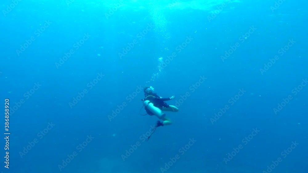 Lone scuba diver swimming through the open blue ocean unreeling a guide rope (slow motion) Lone scuba diver swimming through the open blue ocean unreeling a guide rope (slow motion)