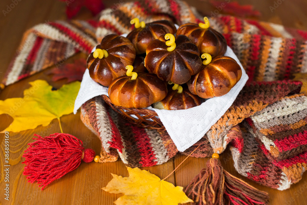 Homemade apple cakes in the shape of pumpkins, cosy colorful shawl or scarf and autumn leaves
