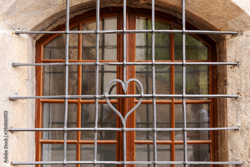 Forged metal grille with a heart in the middle in front of the window